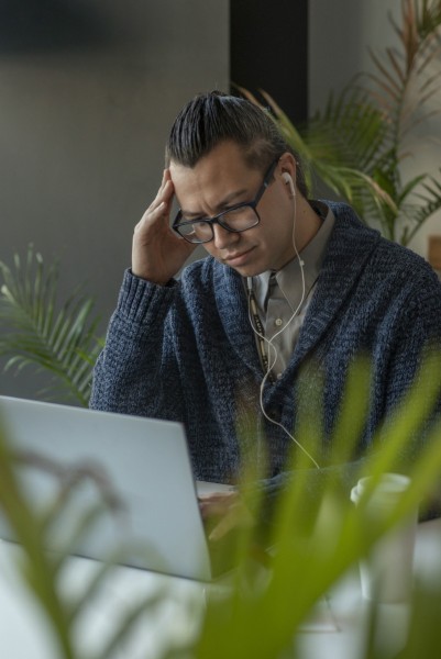 Man frustrated while working on laptop at café