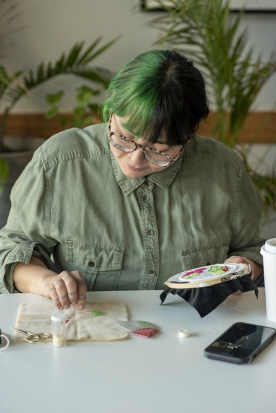 Woman working on beadwork at cafe