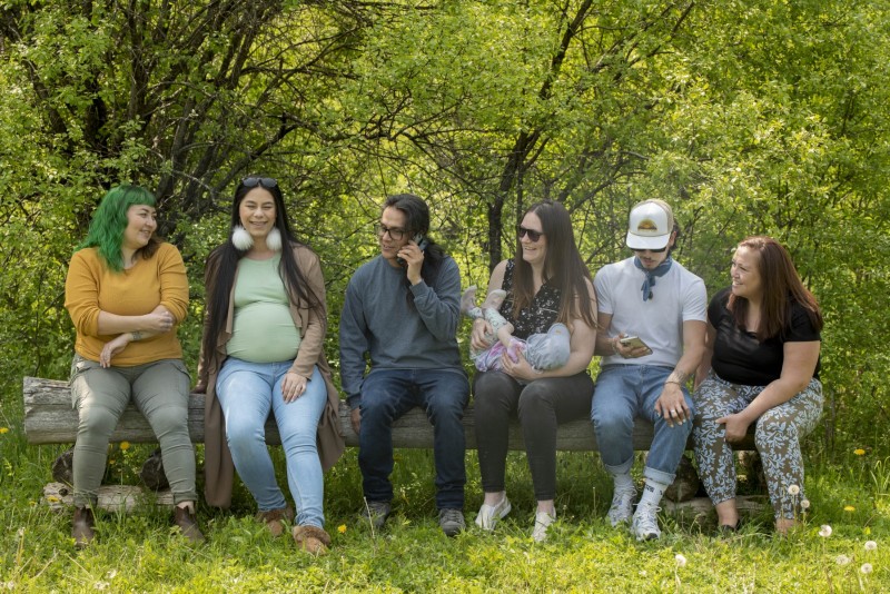 Group of friends sitting on a bench in the forest catching up