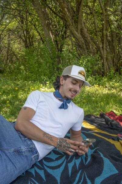 Man relaxing at a picnic, looking at his phone